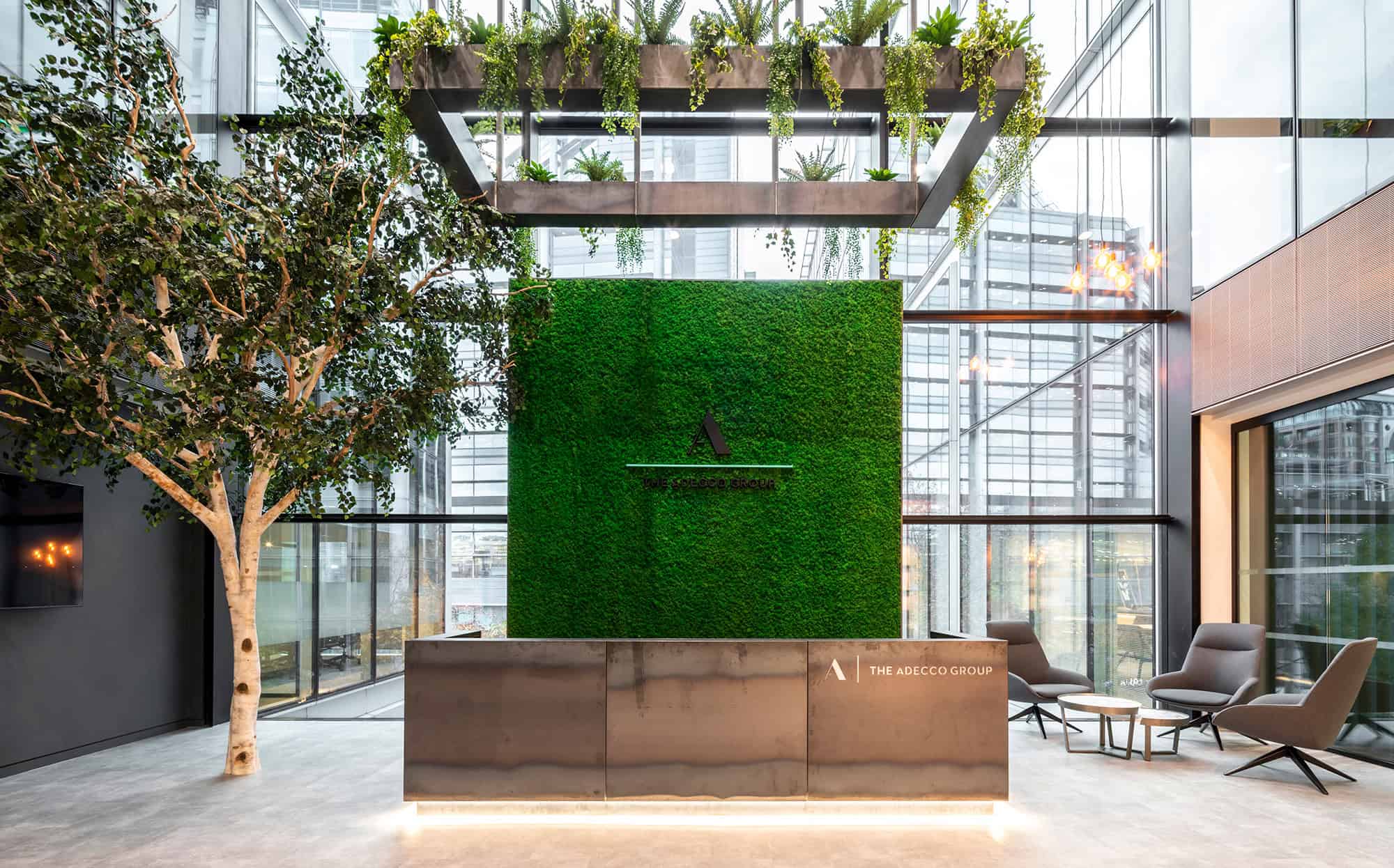 Office reception with a green wall and The Adecco Group signage